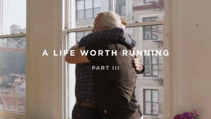 In a sunlit room overlooking the cityscape, two people hug warmly. The text reads, "A Life Worth Running Part III.