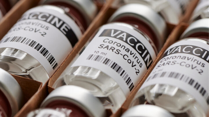 Close-up of COVID vaccines vials labeled "Coronavirus SARS-CoV-2" in a cardboard holder, highlighting the ongoing dialogue about patient distrust and safety assurances among Sermo doctors.