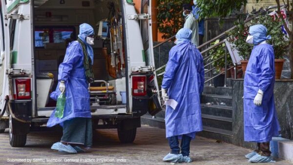 Healthcare workers in protective gear, mindful of physicians' fears, stand near an ambulance, preparing to transport a patient.