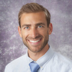 Zachary Horne, MD, smiles warmly in a striped shirt and blue tie against a purple textured backdrop.