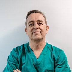 A person in green scrubs, embodying professionalism like the top websites for doctors, stands with arms crossed against a light background.