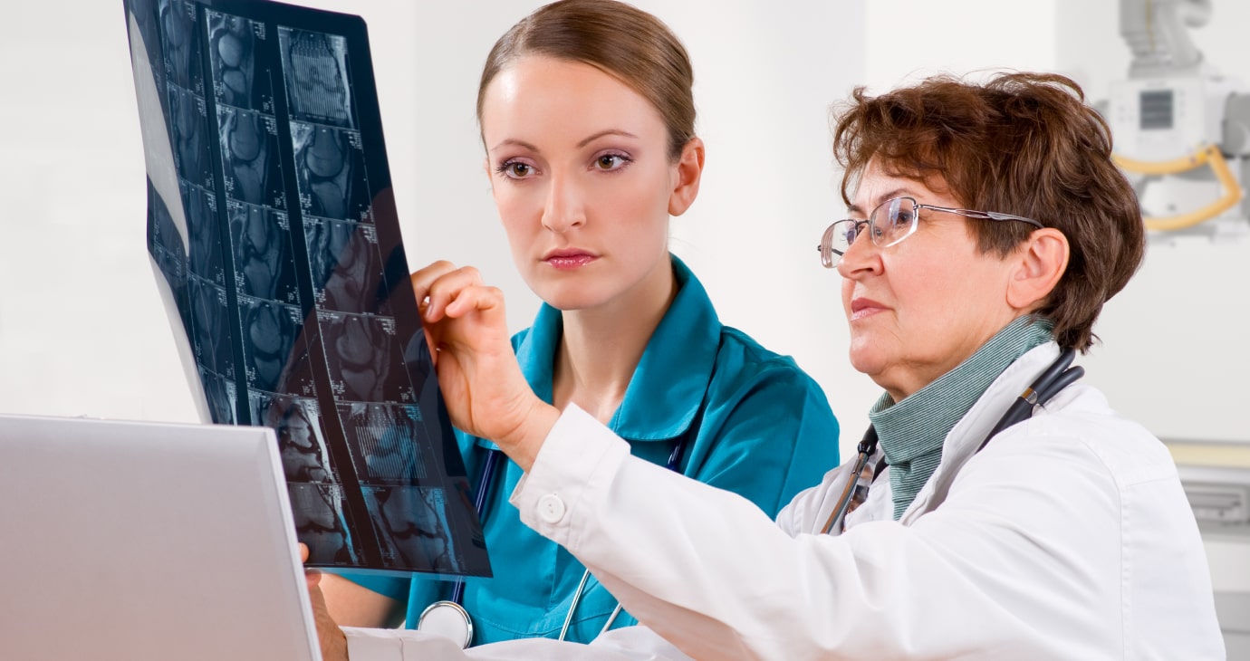 Two healthcare professionals, embodying leadership in their field, examine X-ray images and discuss findings. One wears a white coat with a stethoscope, while the other is in teal scrubs, showcasing the evolution of modern healthcare practices.