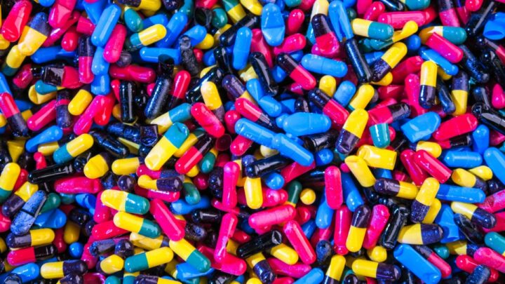 A pile of colorful capsules in red, blue, yellow, and black highlights the important role physicians play in managing medications amidst the opioid epidemic.