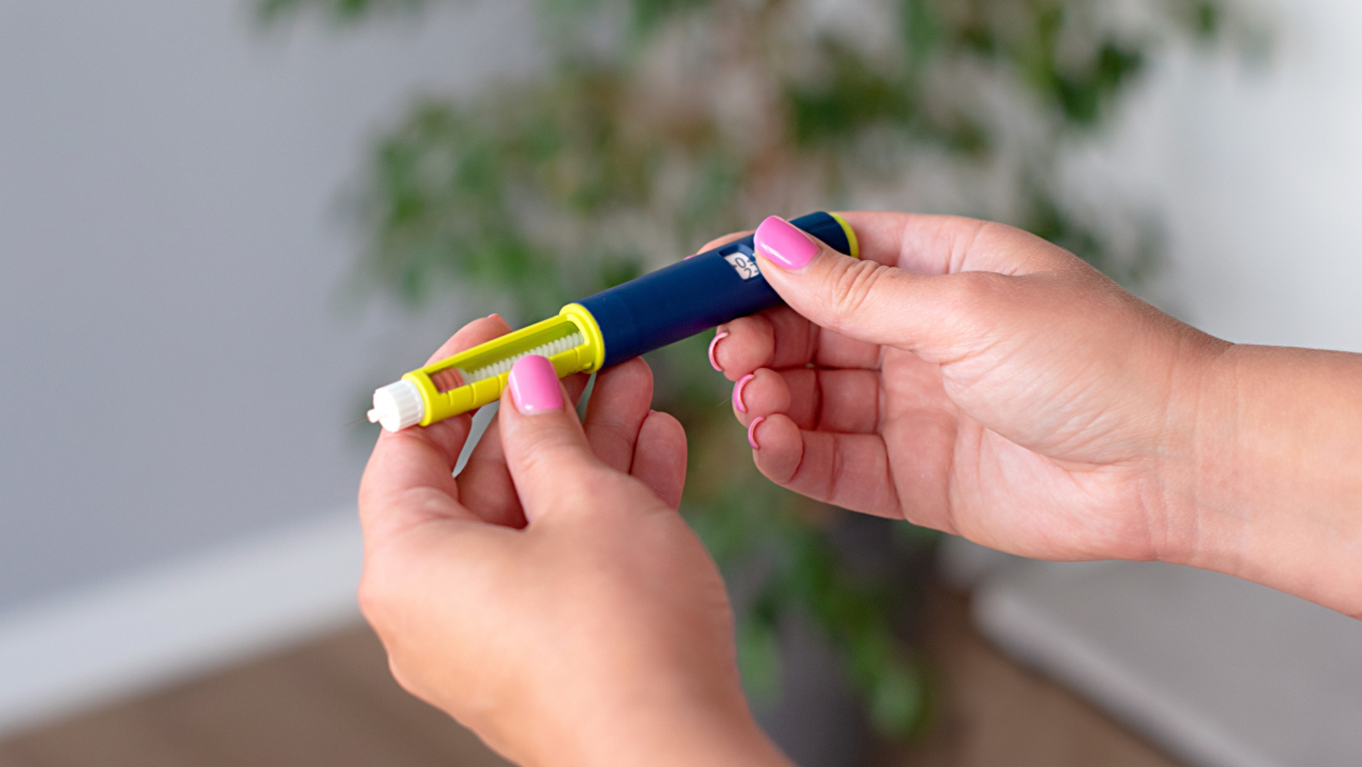 A person holds and prepares an insulin pen, removing the cap with one hand, as doctors often instruct patients on proper technique.