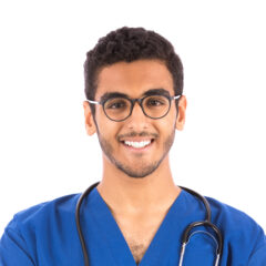 A smiling person wearing glasses and a blue medical scrub, with a stethoscope around their neck, contemplates side gigs for doctors.