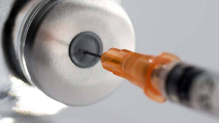 Close-up of a syringe needle carefully inserted into a vial's rubber stopper, set against a neutral background—perfectly illustrating the precise preparation required for managing ketosis-prone diabetes.