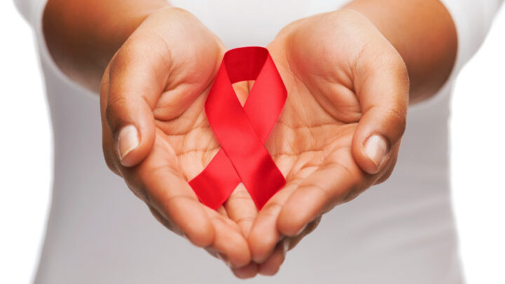 Hands gently cradle a red ribbon, symbolizing support for HIV/AIDS awareness and emphasizing the importance of prevention in women's health.
