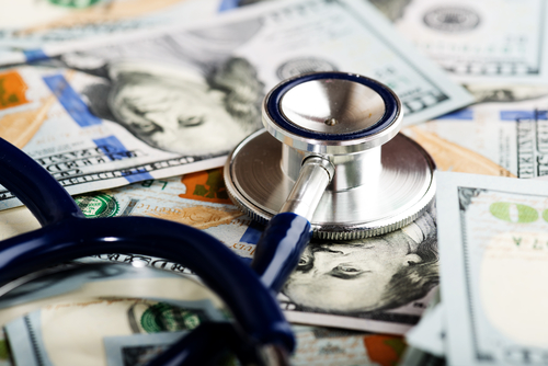 A stethoscope sits atop a stack of U.S. dollar bills, illustrating the intersection of healthcare and finance, where rich doctors navigate their lucrative practices.