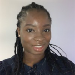 Dr. Abimbola Ekundayo, with braided hair, smiles warmly at the camera against a plain background.